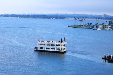 San Diego, CA - 15 Ağustos 2023: Üst güvertesinde turistle birlikte dinlenme amaçlı kürek buharı yavaş yavaş Sail Bay 'in ayna benzeri sularında hareket ediyor.