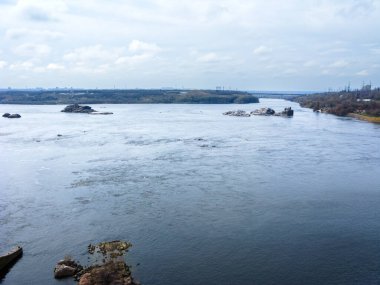 Dnipro nehri Ukrayna 'nın Zaporizhzhia kentindeki Khorytsia adası ve DniproHES barajının güneyinde büyük kayalıklar etrafında bölünüyor. Arka plandaki çekim.