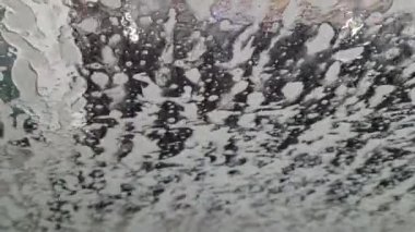 Sabunlu su kabarcıkları ve yanıp sönen ışık çizgileri otomatik bir araba yıkama sürücüsü.