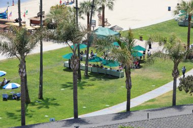 San Diego, CA - June 10, 2024: Bird eye view of cozy outdoor lunch under palms next to sandy beach of Sail Bay marina clipart