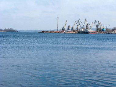 Ukrayna 'nın Zaporizhzhia kentindeki Dnipro' nun sakin suları üzerinde sol nehir kıyısındaki yük gemileri ve liman vinçleri görülüyor.