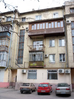 Zaporizhzhya, UA - 3 Mart 2009: Yirminci yüzyılın ortalarında Sovyet mimarisinin tipik arka bahçesi ayrıca Stalin binası olarak da bilinir cam kaplı balkonlar ve modern klima üniteleri yakınlardaki duvarlarda ve arabalarda park halindedir.