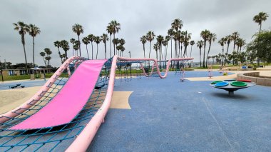 San Diego, CA - 12 Haziran 2024: Bonita Cove rıhtım parkında hala boş olan Maruta Gardner çocuk parkı ile tipik haziran-kasvetli sabahına zıt çocuklar için pembe kaydırma.