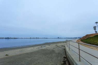 Kumsalın üzerinde yükselen Sail Körfezi önünde kasvetli bir bulutlu sabahta, San Diego, California
