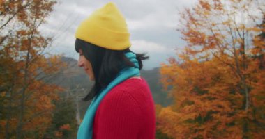 Genç bayan gezgin dağlarda serin sonbahar havasının tadını çıkarıyor ve eğleniyor. Sonbahar soğuk havası. Z kuşağı yolculuğu.