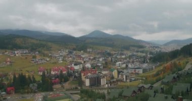 Bukovel kayak merkezinin manzarası, güzel sonbahar ağaçları ve dağlar, uzaktaki evler.
