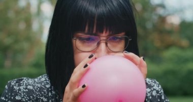 a happy joyful woman inflates balloons and they burst, showing that everything is wrong with condoms and they are torn. playful emotion, pereponyayuschie anger and happiness.