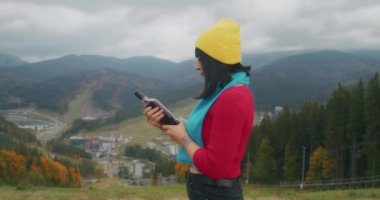 Dağlarda genç bir kadın gezgin sıcak bir içecekle ısınıyor. Sonbahar maceraları. Z kuşağı yolculuğu.