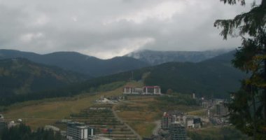 Bukovel kayak merkezinin manzarası, güzel sonbahar ağaçları ve dağlar, uzaktaki evler.