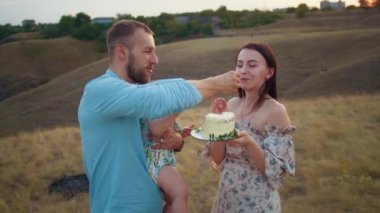 Bebekle mutlu bir aile ilk yılı kutlar, gün batımında, sonbaharda ve yaşam tarzında pasta yerler.