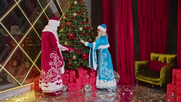 桑塔和桑塔夫人祝圣诞快乐 送上礼物 装饰圣诞树 — 图库视频影像