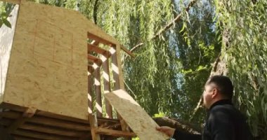 Mutlu baba ve oğul ağaçta bir ev inşa eder, bir çizime bakar, bir ağacı testereyle keser, tornavidayla kendi kendini becerir..