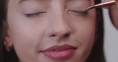 Profesyonel bir fotoğraf stüdyosunda kamera çekimi için modeller hazırlarken. Asyalı bir stilist ve Avrupalı bir makyöz modelleri boyayıp saçlarını yapıyorlar..