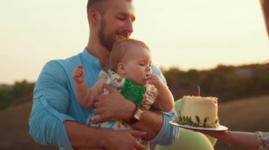 Childs 'ın yaşam tarzı. Sonbahar tarlasında mutlu yıllar. Gün batımında küçük çocuk, çadırda pastayla. Fotoğrafçı doğum günü fotoğrafı çekiyor. Aile ve bebek sevinci