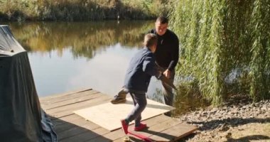 Mutlu baba ve oğul ağaçta bir ev inşa eder, bir çizime bakar, bir ağacı testereyle keser, tornavidayla kendi kendini becerir..