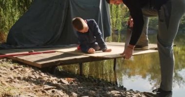 Mutlu baba ve oğul ağaçta bir ev inşa eder, bir çizime bakar, bir ağacı testereyle keser, tornavidayla kendi kendini becerir..