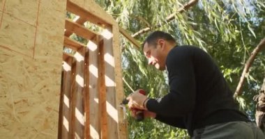 Mutlu baba ve oğul ağaçta bir ev inşa eder, bir çizime bakar, bir ağacı testereyle keser, tornavidayla kendi kendini becerir..