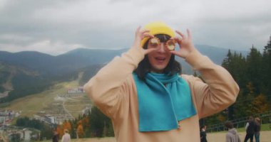 Dağlarda genç bir kadın gezgin sıcak bir içecekle ısınıyor. Sonbahar maceraları. Z kuşağı yolculuğu.