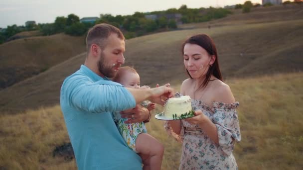 赤ちゃんを持つ幸せな家族は最初の年を祝います 日没でフィールドでケーキを食べます 秋とライフスタイル — ストック動画