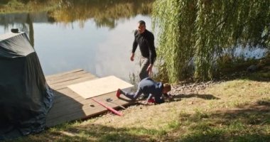 Mutlu baba ve oğul ağaçta bir ev inşa eder, bir çizime bakar, bir ağacı testereyle keser, tornavidayla kendi kendini becerir..