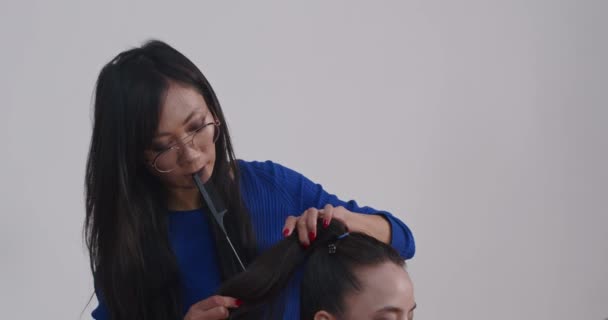 在专业的摄影演播室里准备摄影模特时 在幕后进行表演 一位亚洲造型师和一位欧洲化妆师给模特涂上了颜色 做了头发 — 图库视频影像