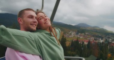 Genç bir çiftin dağlarında tatil, kayak asansörüne tırmanırlar, manzaranın tadını çıkarırlar, duygularını gösterirler..