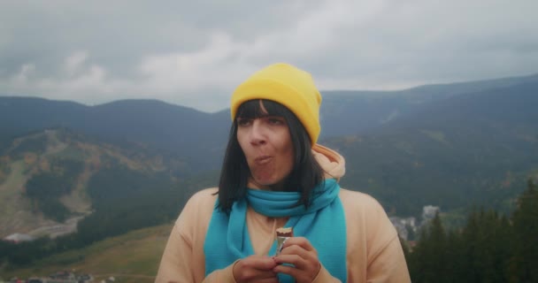 一位年轻的女旅行家在山上吃着雀巢巧克力棒 享受着它的美味 — 图库视频影像