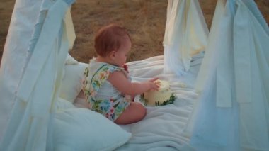 Childs 'ın yaşam tarzı. Sonbahar tarlasında mutlu yıllar. Gün batımında küçük çocuk, çadırda pastayla. Fotoğrafçı doğum günü fotoğrafı çekiyor. Aile ve bebek sevinci