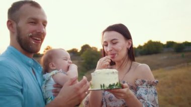 Bebekle mutlu bir aile ilk yılı kutlar, gün batımında, sonbaharda ve yaşam tarzında pasta yerler.