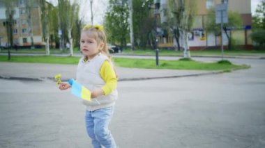 Sarışın kız, çiçek açan pembe sakura çiçeklerinin arka planında bir karahindibayı uçuruyor. Gün batımında gülümseyerek hafta sonu yürüyüşü