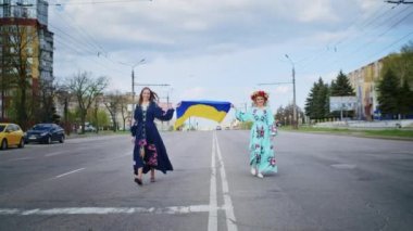 İki mutlu kadın sevinir ve Ukrayna bayrağıyla yol boyunca yürür. Hafta sonu yürüyüşü, gün batımında bir gülümsemeyle. Kadın ve bahar