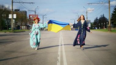 İki mutlu kadın sevinir ve Ukrayna bayrağıyla yol boyunca yürür. Hafta sonu yürüyüşü, gün batımında bir gülümsemeyle. Kadın ve bahar