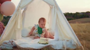Childs 'ın yaşam tarzı. Sonbahar tarlasında mutlu yıllar. Gün batımında küçük çocuk, çadırda pastayla. Fotoğrafçı doğum günü fotoğrafı çekiyor. Aile ve bebek sevinci