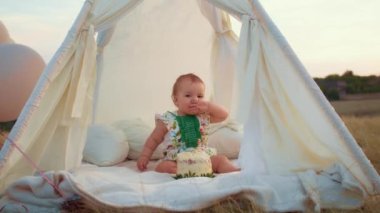 Childs 'ın yaşam tarzı. Sonbahar tarlasında mutlu yıllar. Gün batımında küçük çocuk, çadırda pastayla. Fotoğrafçı doğum günü fotoğrafı çekiyor. Aile ve bebek sevinci