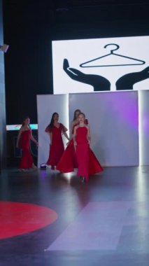 Podyumdaki kadın kıyafetlerinin moda tasarımı, renkli elbiseli güzel bir kızın lekelenmesi bir model şovunun podyumunda, dikey video