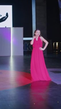 Podyumdaki kadın kıyafetlerinin moda tasarımı, renkli elbiseli güzel bir kızın lekelenmesi bir model şovunun podyumunda, dikey video