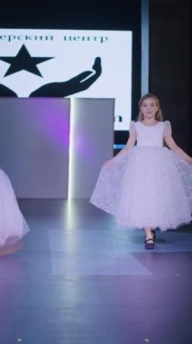 Podyumdaki kadın kıyafetlerinin moda tasarımı, renkli elbiseli güzel bir kızın lekelenmesi bir model şovunun podyumunda, dikey video