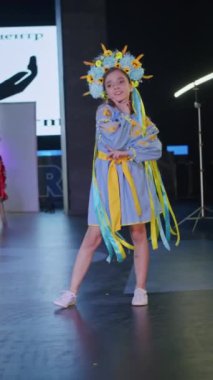 Podyumdaki kadın kıyafetlerinin moda tasarımı, renkli elbiseli güzel bir kızın lekelenmesi bir model şovunun podyumunda, dikey video