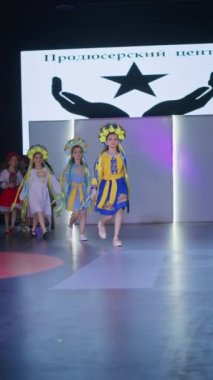 Podyumdaki kadın kıyafetlerinin moda tasarımı, renkli elbiseli güzel bir kızın lekelenmesi bir model şovunun podyumunda, dikey video
