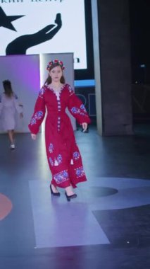 Podyumdaki kadın kıyafetlerinin moda tasarımı, renkli elbiseli güzel bir kızın lekelenmesi bir model şovunun podyumunda, dikey video