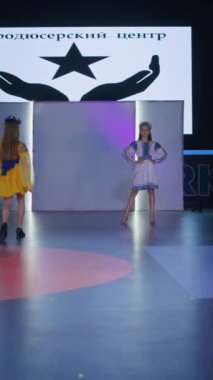 Podyumdaki kadın kıyafetlerinin moda tasarımı, renkli elbiseli güzel bir kızın lekelenmesi bir model şovunun podyumunda, dikey video