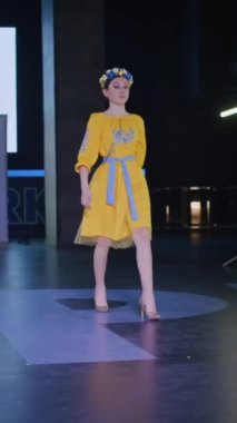 Podyumdaki kadın kıyafetlerinin moda tasarımı, renkli elbiseli güzel bir kızın lekelenmesi bir model şovunun podyumunda, dikey video