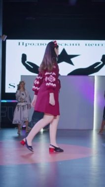 Podyumdaki kadın kıyafetlerinin moda tasarımı, renkli elbiseli güzel bir kızın lekelenmesi bir model şovunun podyumunda, dikey video