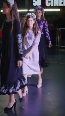 Podyumdaki kadın kıyafetlerinin moda tasarımı, renkli elbiseli güzel bir kızın lekelenmesi bir model şovunun podyumunda, dikey video