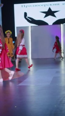 Podyumdaki kadın kıyafetlerinin moda tasarımı, renkli elbiseli güzel bir kızın lekelenmesi bir model şovunun podyumunda, dikey video