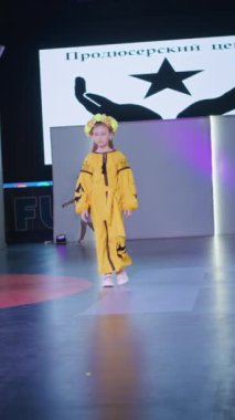 Podyumdaki kadın kıyafetlerinin moda tasarımı, renkli elbiseli güzel bir kızın lekelenmesi bir model şovunun podyumunda, dikey video