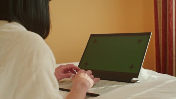 看着一位年轻女性从家里的沙发上微笑着 一边在笔记本电脑上工作 一边在检疫过程中通过电子邮件与客户沟通 所有这些都在绿色屏幕上进行着 — 图库视频影像