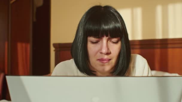この感動的なビデオでは 隔離中に自宅で働く若い女性は 彼女が笑顔で コンピュータに入力し 快適なソファに座っている間に電子メールを送信することができることを示しています — ストック動画