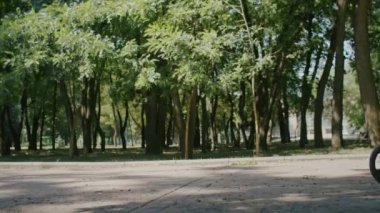 Neşeli kız yazın tadını çıkarıyor ve park ve şehir sokaklarında scooter sürüyor.