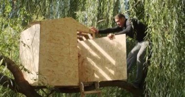 Mutlu baba ve oğul ağaçta bir ev inşa eder, bir çizime bakar, bir ağacı testereyle keser, tornavidayla kendi kendini becerir..